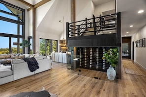 Amplia sala de estar con techo alto, chimenea y escalera que lleva a un nivel superior.
