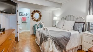 Ein Schlafzimmer mit einem Bett, einem Nachttisch und einem Fernseher auf einem Schrank.