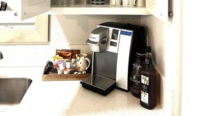Ein Küchenschrank mit Regalen, auf denen verschiedenes Glas, weiße Schüsseln und eine Kaffeemaschine stehen.