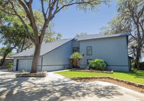 A single-story house with a garage, a front yard with a palm tree, and a stone planter.