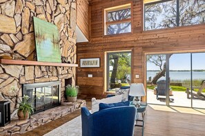 A stone fireplace, wooden walls, a large window, and a view of the outdoors. - Lakeside Villa (Thonotosassa)