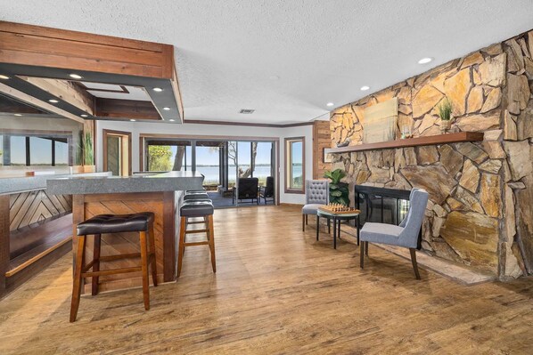 A spacious kitchen with a bar area, stone wall, and a view of the outdoors.