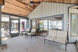 An outdoor patio with a ceiling fan, two chairs, and a table.