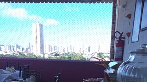 Un área de comedor al aire libre con mesas dispuestas para el desayuno, un extintor y vistas del horizonte de la ciudad.
