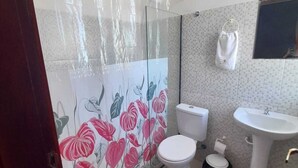 Un baño con cortina de ducha, inodoro, lavabo y pared con azulejos.
