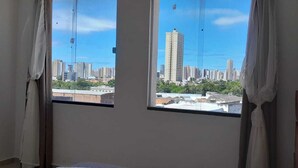 Una habitación con dos ventanas que dan a una vista panorámica de la ciudad, con edificios altos.
