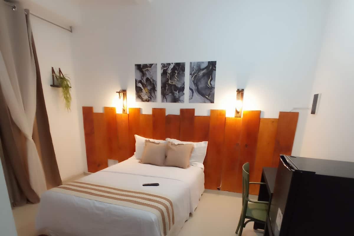 A bedroom with a bed, a desk, and a chair.
