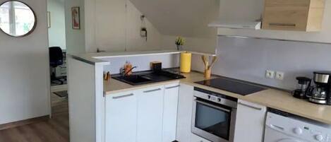 A compact kitchen with white cabinetry, a built-in oven, a microwave, and a washing machine.