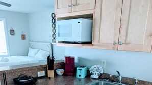 A compact kitchen with wooden cabinets, a microwave, a sink, and a toaster. - Relaxing Studio Apt - Central MB (Myrtle Beach)