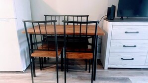 A dining area with a wooden table and chairs, a white refrigerator, a white cabinet with drawers, and a flat-screen TV on top. - Relaxing Studio Apt - Central MB (Myrtle Beach)