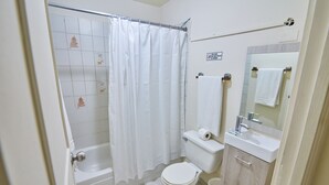 A bathroom with a bathtub, toilet, sink, and a mirror.