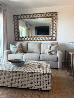 Ein Wohnzimmer mit einer Couch, einem Couchtisch, einem Ziertepiegel und einem Fernseher.