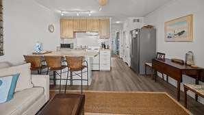 A compact kitchen with wooden cabinets, a central island, and a dining area with a wooden table and chairs. - 3rd Floor Oceanfront Condo!! Community Pool & 1000 ft Fishing Pier! *Unit 308, Bldg A* (Isle Of Palms)