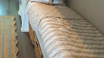 A bed with a quilted cover, a starfish pillow, and a woven basket at the foot.