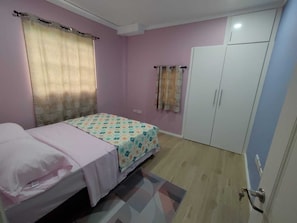 Een slaapkamer met een bed, een kledingkast en een deur.