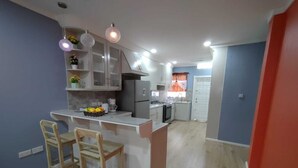 A modern kitchen with a central island, two bar stools, and a dining table.