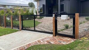 A modern house with a patio area, a fenced yard, and a sign indicating it's a 'Cockatoo Cottage'. - Cockatoo Cottage Bundeena (Bundeena)