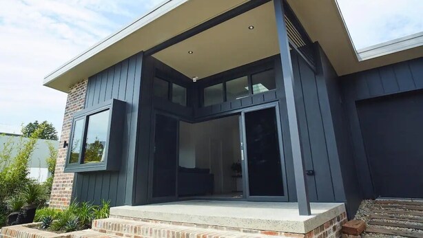 A modern house with a large glass door and a covered porch. - Cockatoo Cottage Bundeena (Bundeena)
