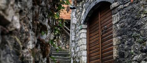 Un bâtiment en pierre avec une porte en bois et un escalier en pierre menant à l’entrée.