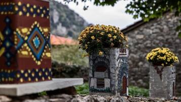 A stone structure with a flower pot on top, set against a mountainous backdrop.
