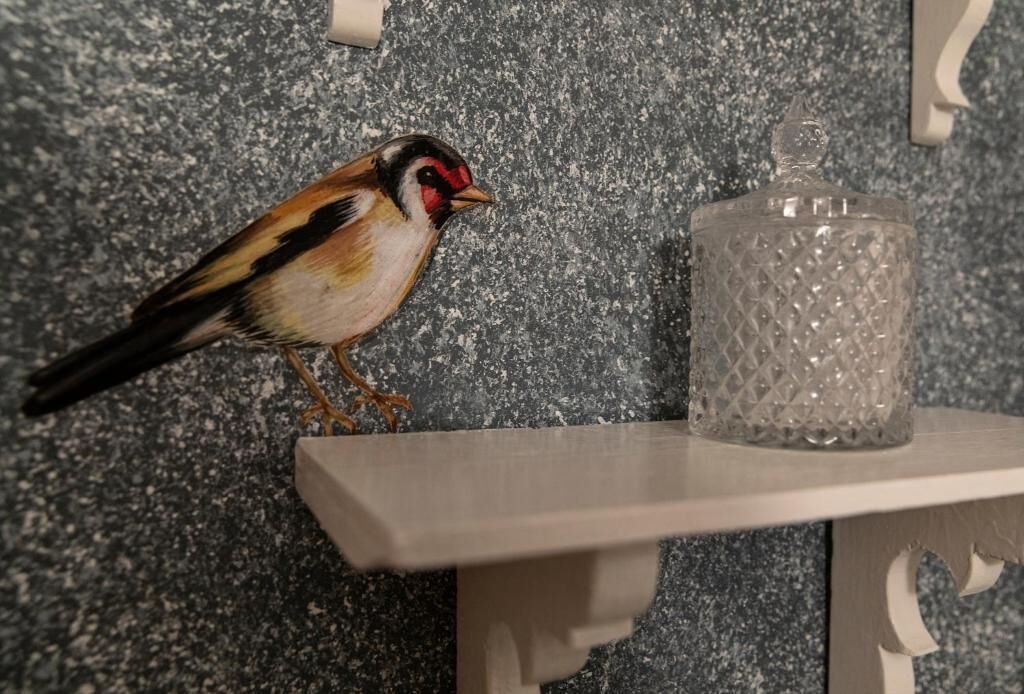 Un oiseau perché sur une étagère, à côté d’un récipient en verre.