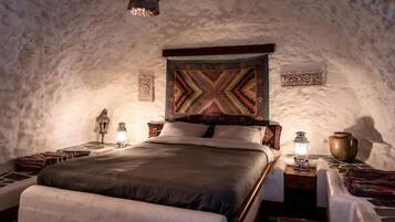 A cozy, rustic bedroom with a large bed, a hanging light fixture, and a decorative wall hanging.