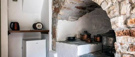 Una cocina con un arco de piedra, un refrigerador blanco y varias ollas y sartenes sobre la encimera.