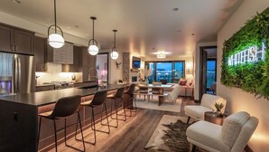Una cocina moderna con una isla central, taburetes de bar, iluminación colgante y un comedor con vistas.