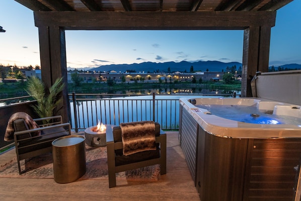 Un jacuzzi con revestimiento de madera, un brasero y una silla con una manta de piel.