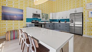 Une cuisine moderne dotée d’un îlot central, de meubles blancs et d’un pare-feu orné de carreaux bleus.