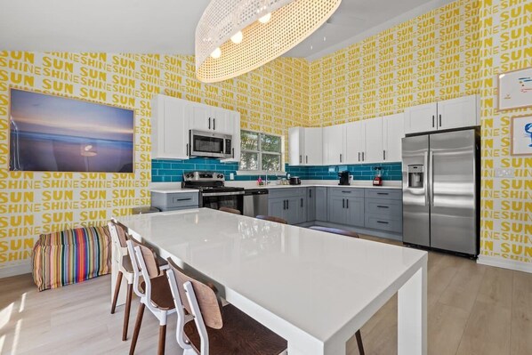 A modern kitchen with a central island, white cabinets, and a backsplash with blue tiles.