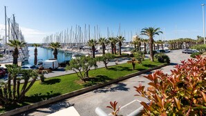 A marina with numerous boats docked, surrounded by palm trees and a clear blue sky.