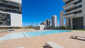 A swimming pool with lounge chairs, a fountain, and modern buildings in the background. - CostaBlancaDreams - Alexia in Calpe (Calpe)