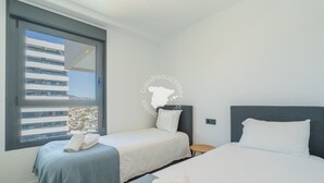 A hotel room with two beds, a small table, and a window with a view of a building. - CostaBlancaDreams - Alexia in Calpe (Calpe)