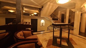 A spacious living room with a grand piano, a chandelier, and a staircase leading to an upper level. - Hotel & Suites Gonsalez Suarez Quito (Quito)