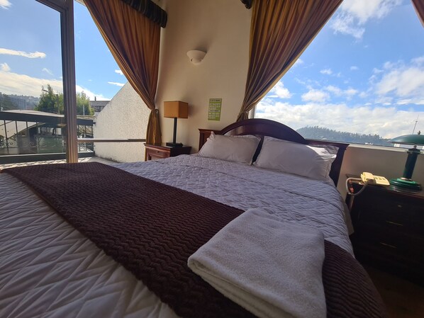 A hotel room with a large bed, a view of the city, and a balcony. - Hotel & Suites Gonsalez Suarez Quito (Quito)