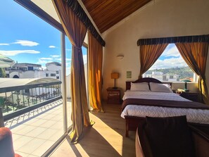 A hotel room with a balcony, a bed, a nightstand, and a view of the cityscape. - Hotel & Suites Gonsalez Suarez Quito (Quito)