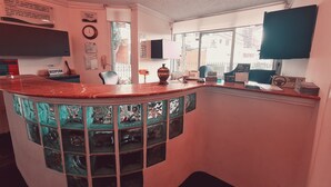 A hotel reception area with a marble counter, a reception desk, a clock, and a window with a view of buildings. - Hotel & Suites Gonsalez Suarez Quito (Quito)