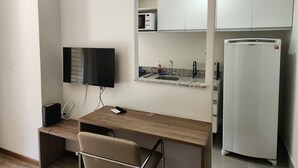 A small, modern room with a wooden desk, a chair, a flat-screen TV, a built-in sink, and a refrigerator. - Flat near the river Center/Barra Olímpica (Rio de Janeiro)
