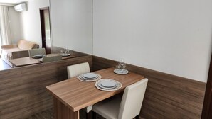 A dining area with a wooden table set for four, including plates, cutlery, and glasses. - Flat near the river Center/Barra Olímpica (Rio de Janeiro)