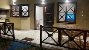 A covered outdoor area with a wooden bench, a metal gate, and a tiled floor.