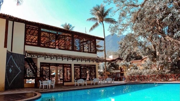 A two-story building with a swimming pool, outdoor seating, and palm trees.