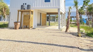 A two-story white building with a covered entrance and a gravel driveway. - The Beach Lily - South Cape San Blas - Pet Friendly (Port St. Joe)