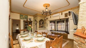 A dining area with a large table set for a meal, wooden chairs, and a stone fireplace. - RINCON DE LA HUERTA - Fantastic house with elevated pool and free WIFI (Chiclana de la Frontera)