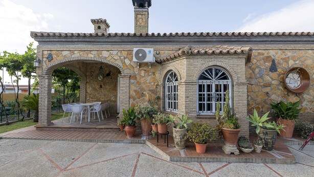 A stone building with a tiled roof, a chimney, and a patio area with a table and chairs. - RINCON DE LA HUERTA - Fantastic house with elevated pool and free WIFI (Chiclana de la Frontera)