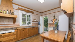 A kitchen with wooden cabinets, a granite countertop, and a dining table. - RINCON DE LA HUERTA - Fantastic house with elevated pool and free WIFI (Chiclana de la Frontera)