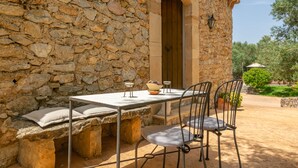 Un edificio de piedra con una mesa y sillas afuera.