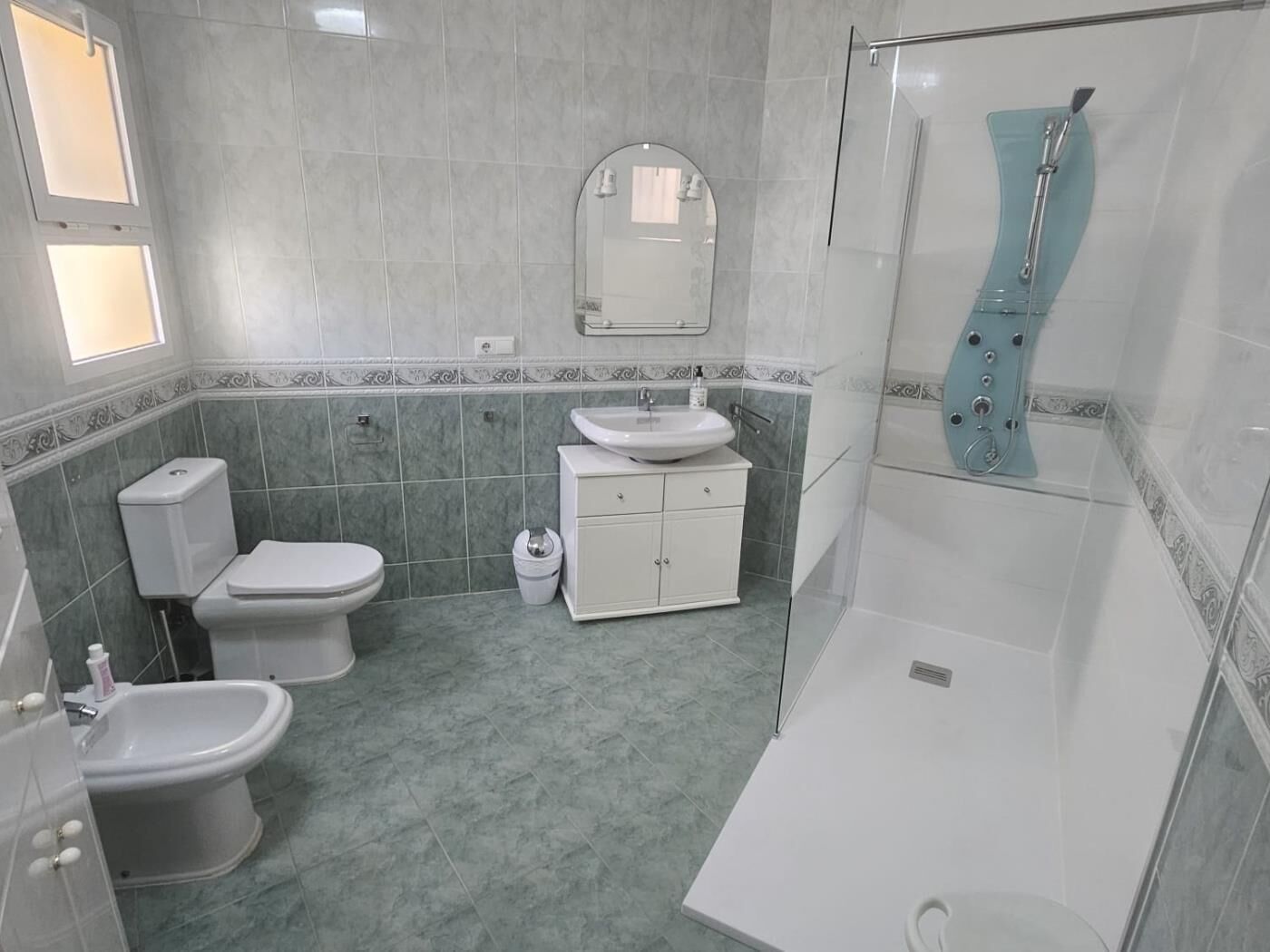A bathroom with a toilet, bidet, sink, and shower.
