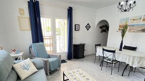 Una sala de estar con sofá, mesa de centro, mesa de comedor con sillas y una araña.
