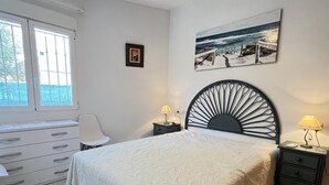Un dormitorio con cama, mesita de noche, silla, cómoda y ventana.